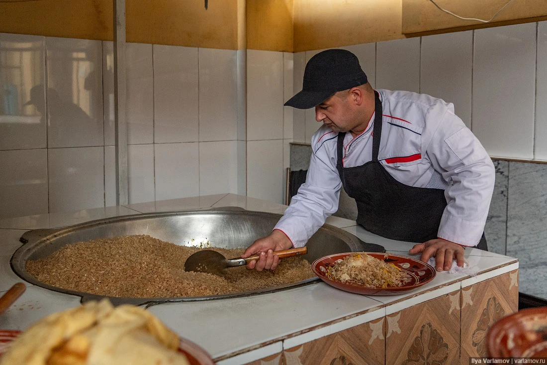 Plov di Samarcanda servito a strati su un grande piatto ovale: riso in collina, carote e carne sopra, teste d'aglio e uova sode come decorazione Plov di Samarcanda servito a strati su un grande piatto ovale: riso in collina, carote e carne sopra, teste d'aglio e uova sode come decorazione