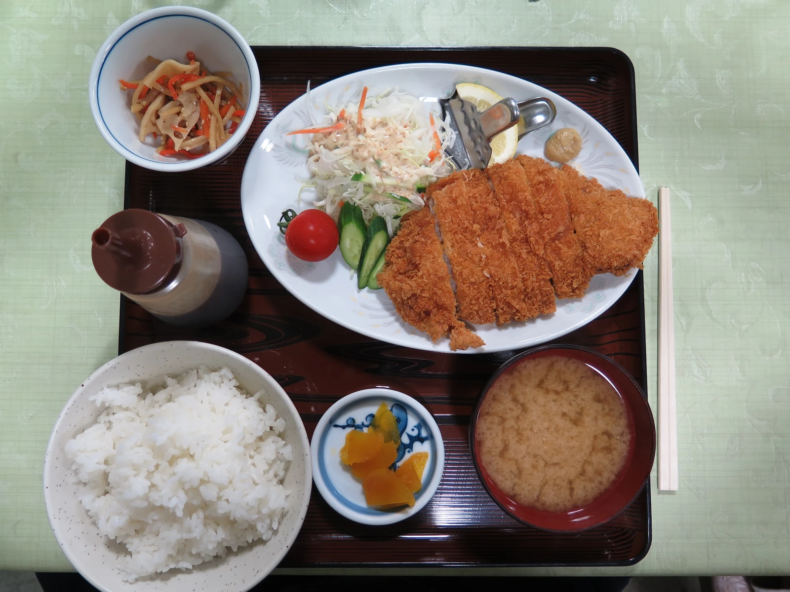 Piatto di tonkatsu con cavolo tagliato sottile, spicchio di limone e salsa